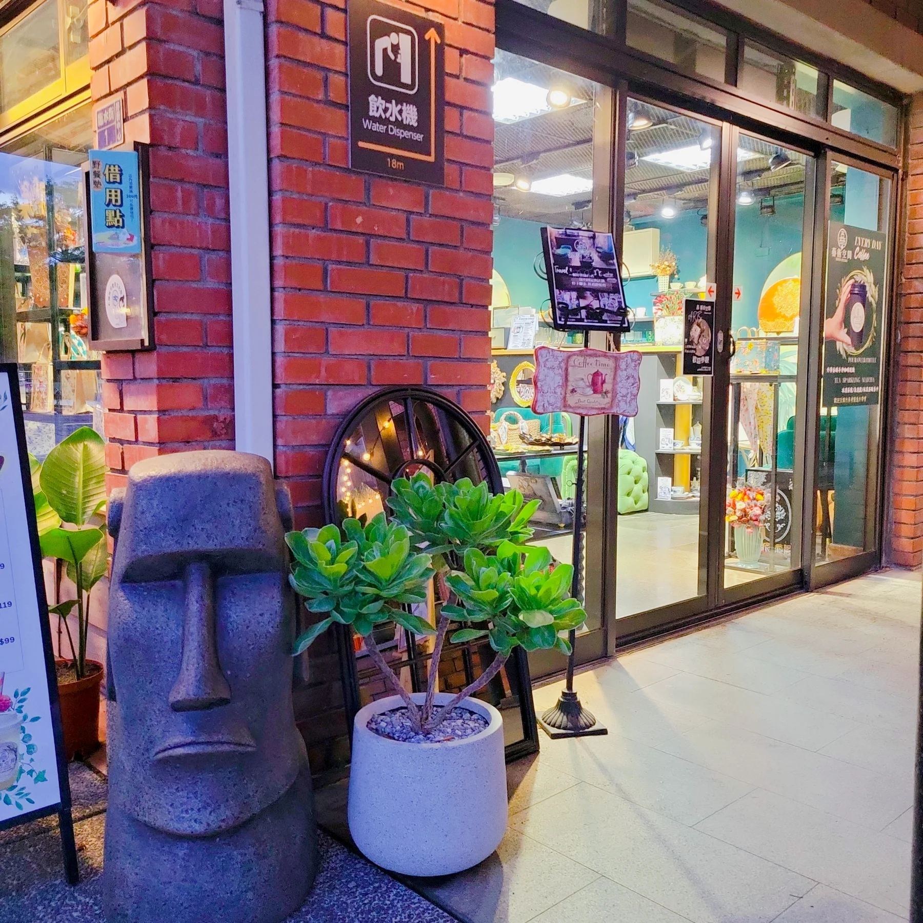 紅磚廊道、入口植栽、造型雕塑與店面櫥窗形成的迎賓陳列